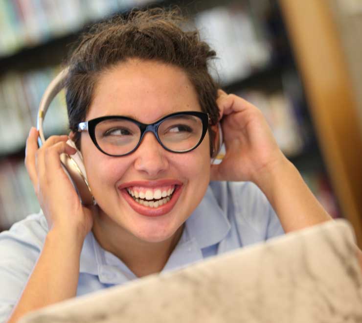 Student listening to headphones in the Library & Media Center.